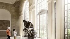 A woman and child looking at Rodin's The Thinker