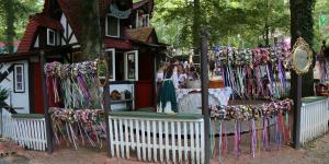 Festival grounds with a cottage and traditionally dressed women